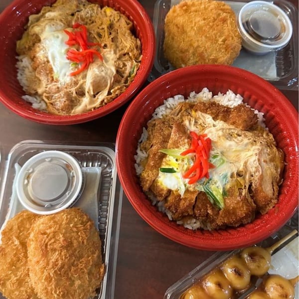 Two FuruSato Bento bowls with rice, egg, and katsu, plus side dishes including croquettes and dango.