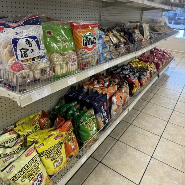 Shelves filled with various Japanese snacks and chips, including rice crackers and corn puffs.